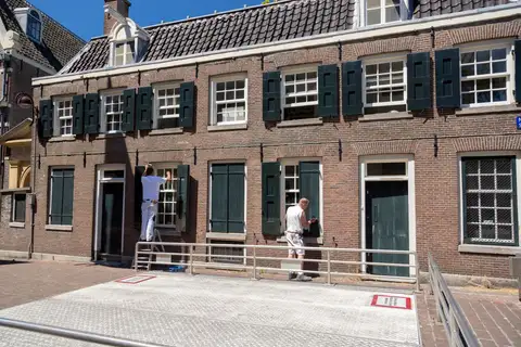 Painters refurbishing a house exterior facade on a sunny day