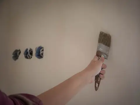 Painter applying interior wall paint with a brush